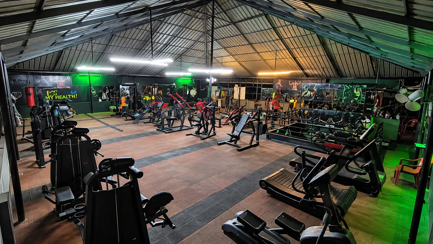 Wide view of the My Health Fitness Industry gym floor in Kottarakkara, with rows of strength machines under a high steel roof